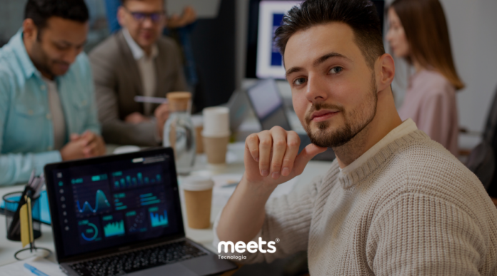 Profissional analisando dados em um dashboard no notebook durante reunião de equipe, representando análise estratégica e tomada de decisão com CRM e inteligência de dados.