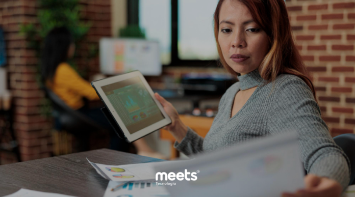 Profissional analisando relatórios de desempenho e dados de vendas em tablet, representando a análise de resultados comerciais e tomada de decisão no fechamento de mês.