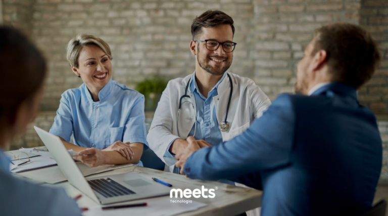 Equipe médica realizando atendimento humanizado em clínica, com médicos conversando e cumprimentando paciente durante reunião, representando experiência personalizada e atendimento concierge na área da saúde.