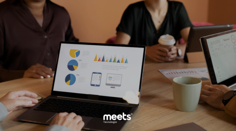 Equipe de agência analisando métricas de marketing e gestão de leads em reunião estratégica, utilizando dashboards em notebooks para acompanhar desempenho de campanhas, funis de vendas e atendimento centralizado com CRM.