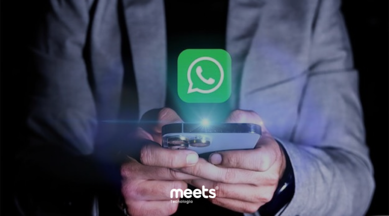 Um close-up das mãos de uma pessoa com terno segurando um smartphone que brilha com o ícone do WhatsApp pairando acima dele, representando a eficiência do atendimento.